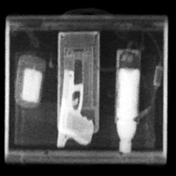 A Z Backscatter X-ray image of a briefcase exposes a Glock handgun and plastic and liquid explosives, highlighted in white. (AS&E)