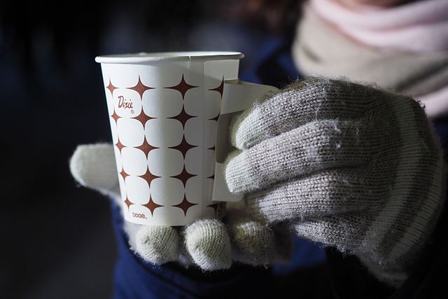 Hands in gloves holding coffee